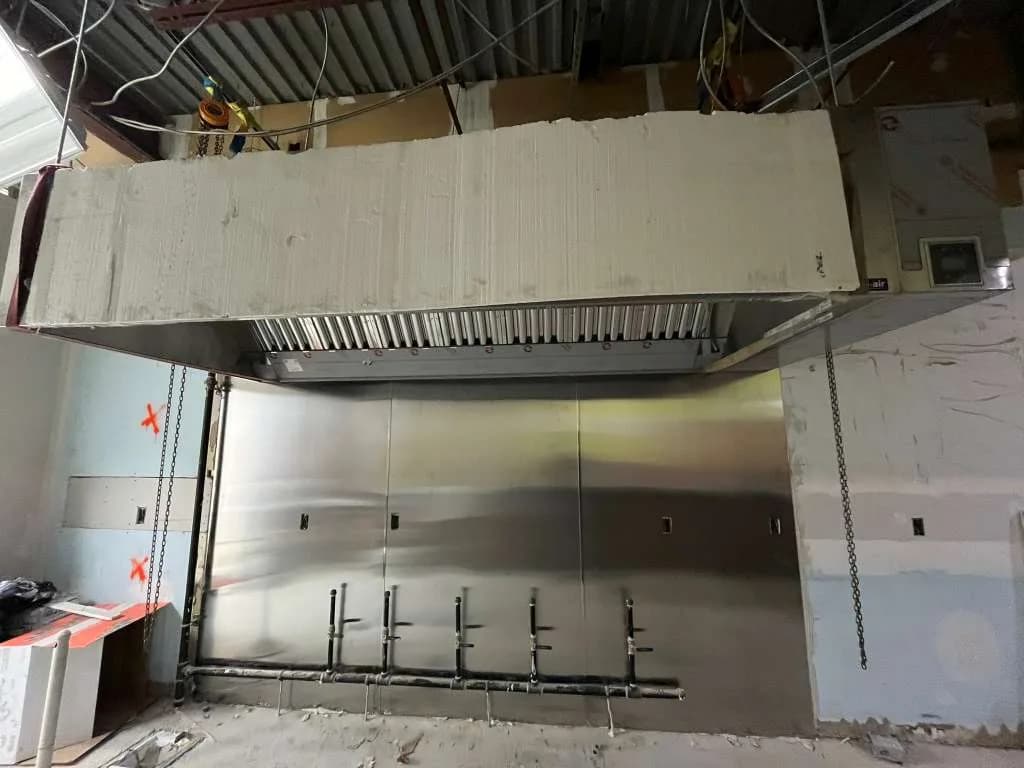 Large stainless steel CaptiveAire exhaust hood mounted during kitchen build-out