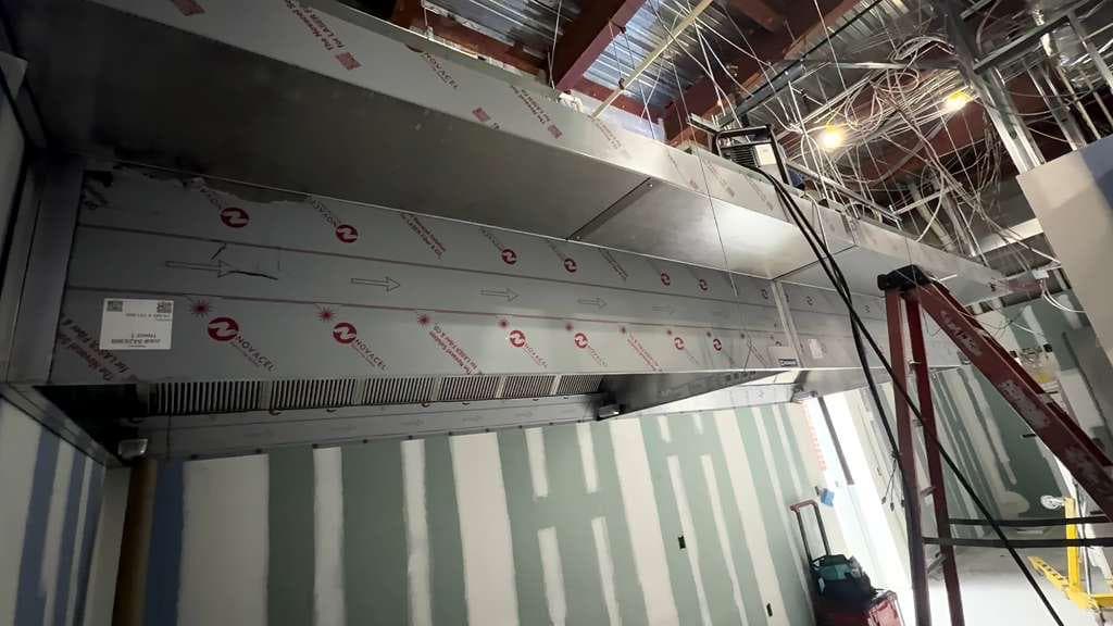 Technician cleaning a commercial kitchen exhaust system